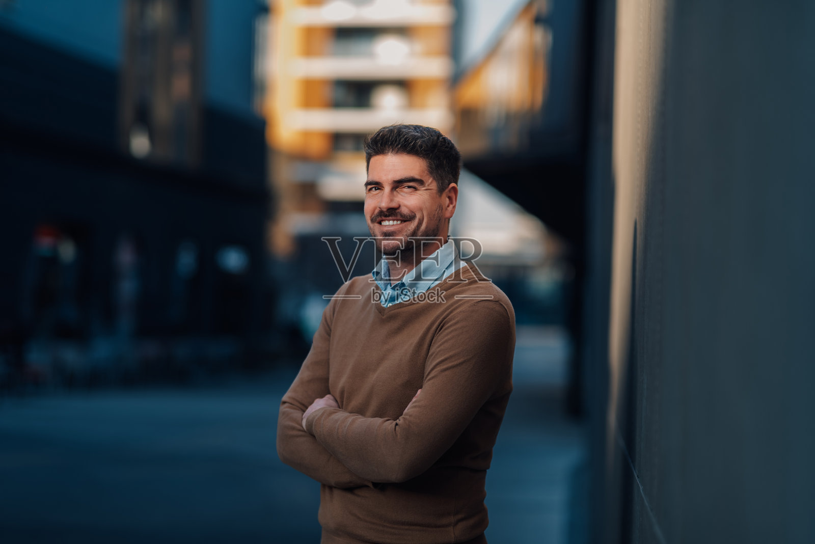 微笑的商人在城市环境中双臂交叉站立照片摄影图片