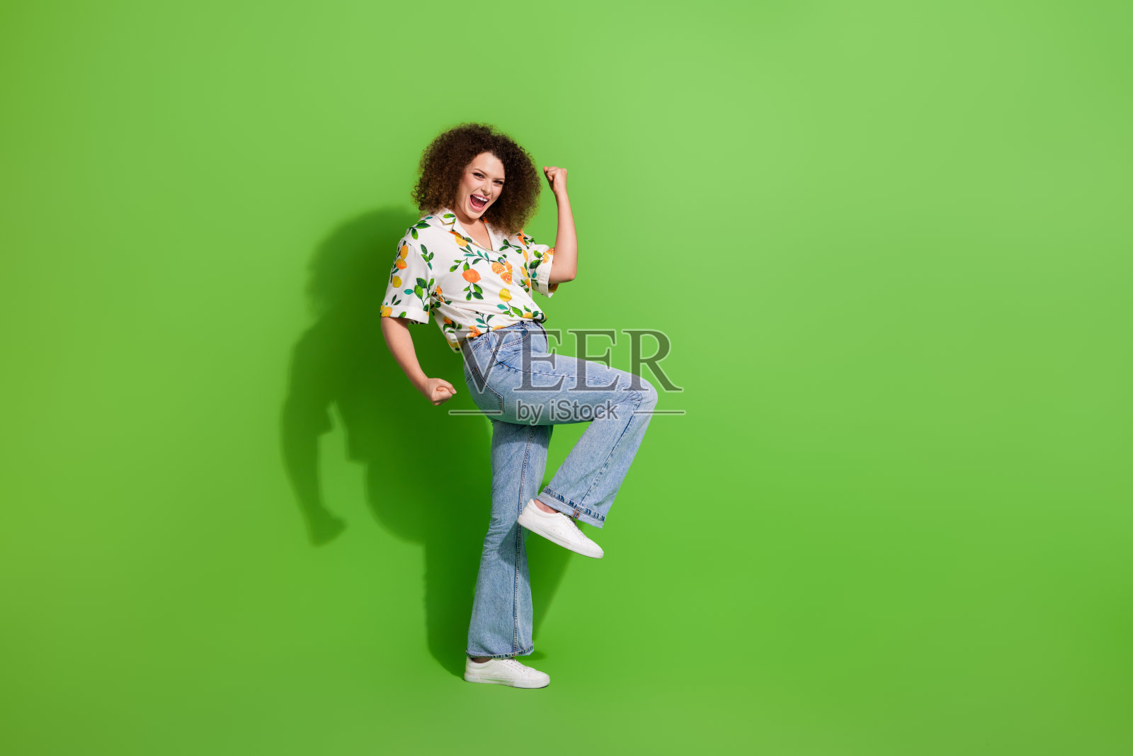 全身侧面照，开心的女士举起拳头庆祝成就，背景为空旷的绿色。照片摄影图片