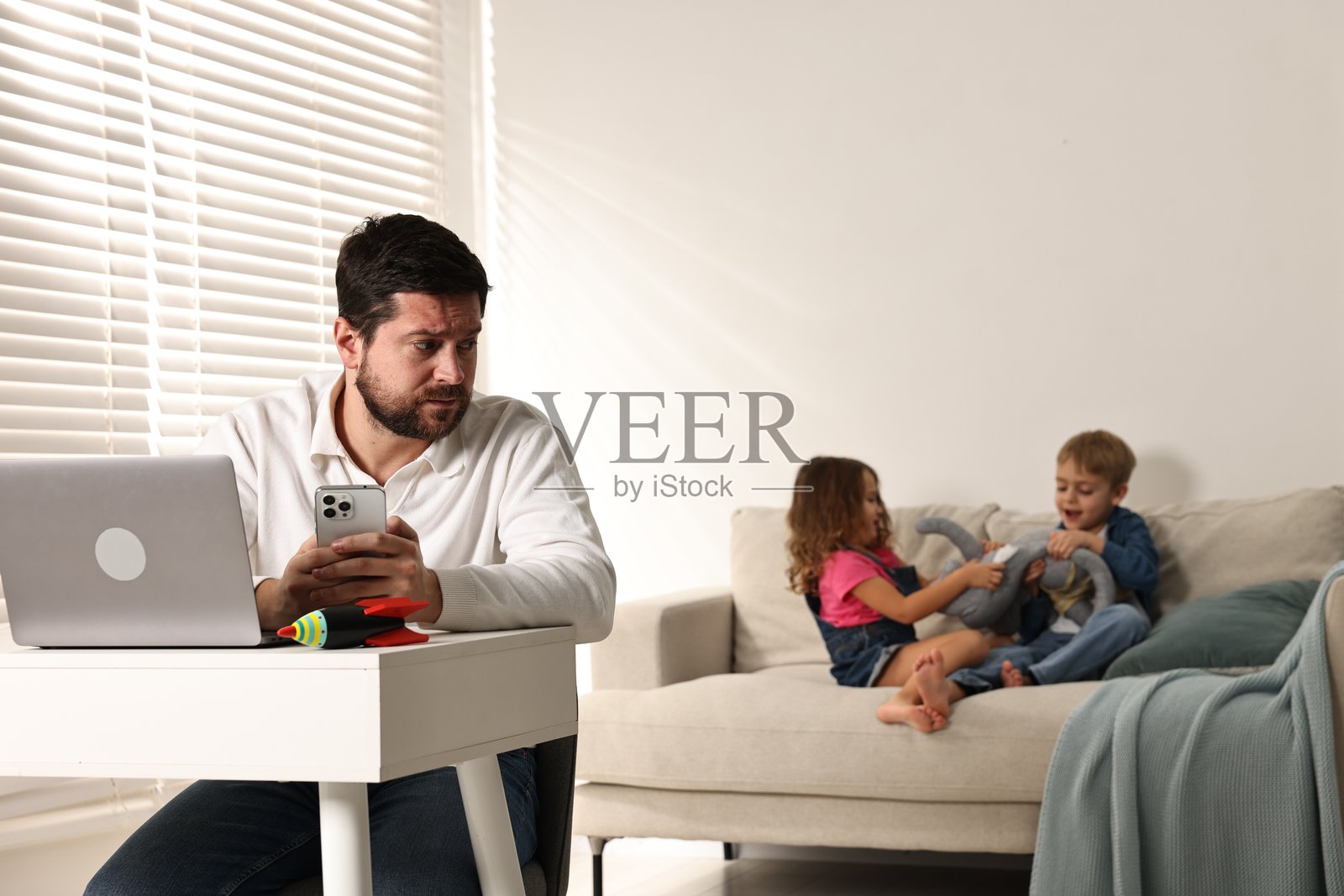 调皮的孩子们在家里打扰感到不堪重负的父亲照片摄影图片