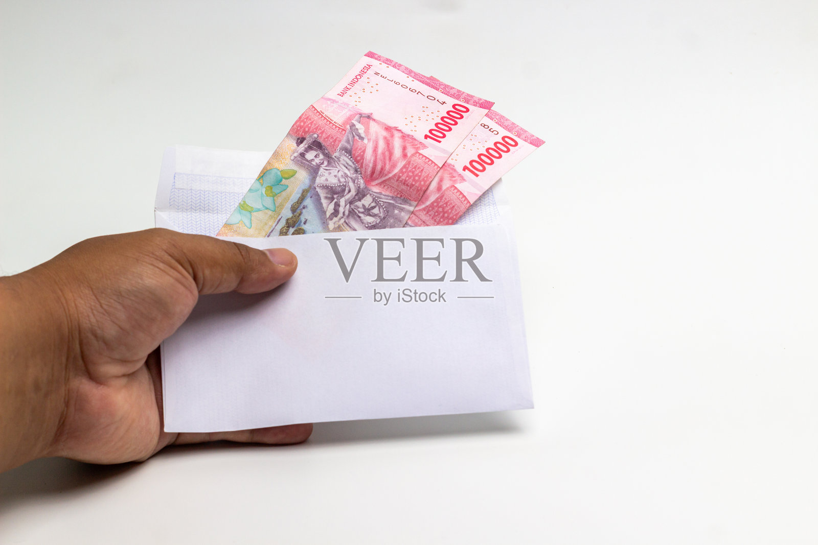 亚洲印尼男子手中展示装有印尼盾的信封。照片摄影图片