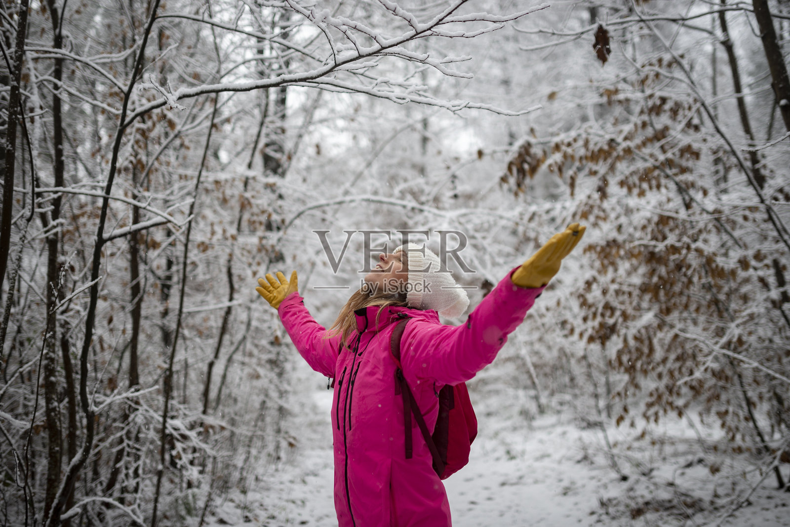 年轻女性穿着粉色冬季外套，在白雪皑皑的大自然中庆祝并享受生活照片摄影图片