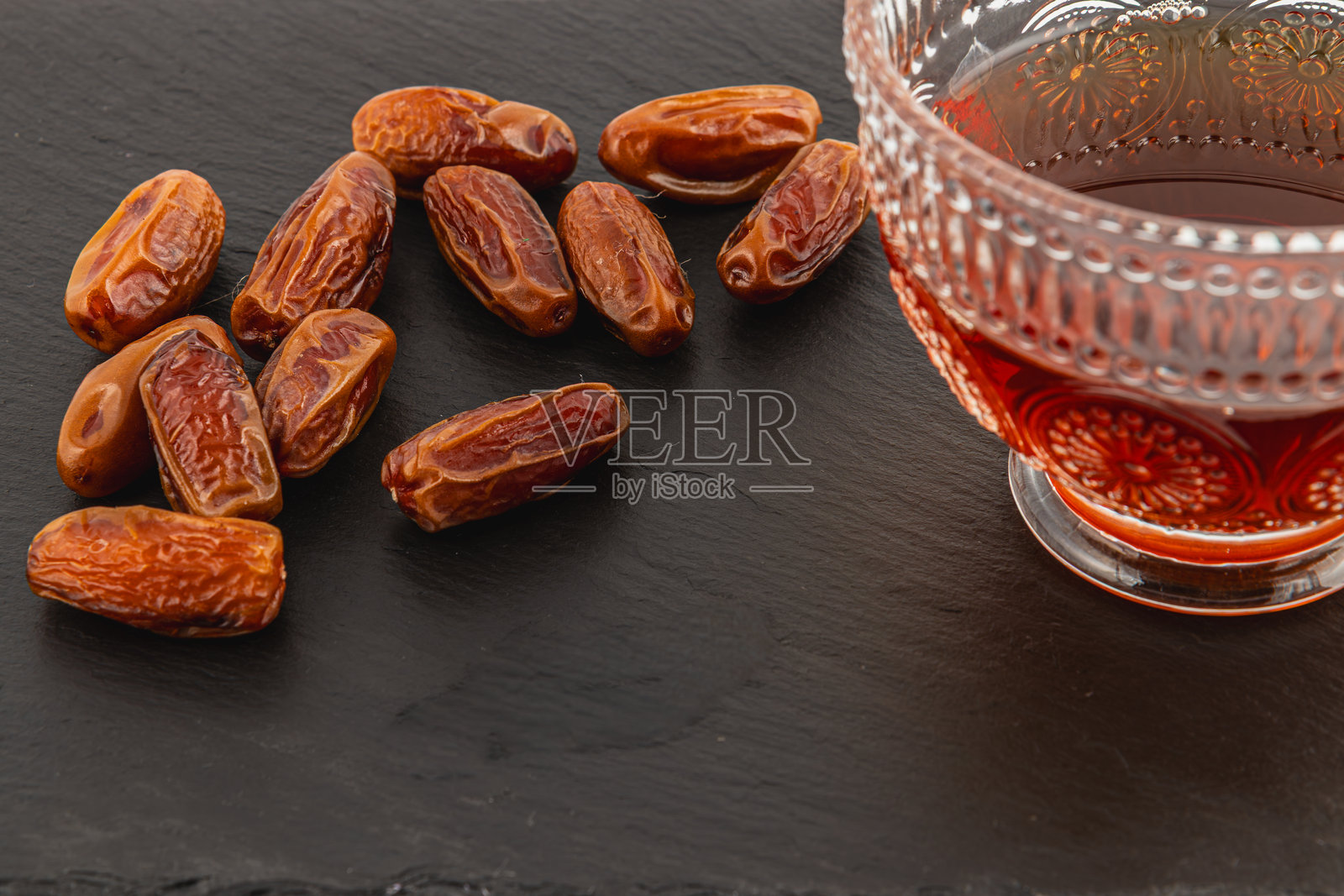 温暖的枣子和茶在深色托盘上的舒适摆放照片摄影图片