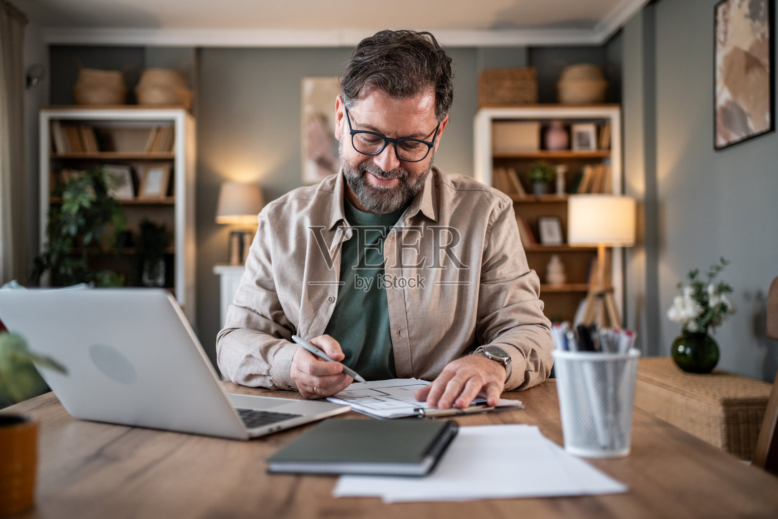 微笑的成熟自由职业者在家办公时做笔记照片摄影图片