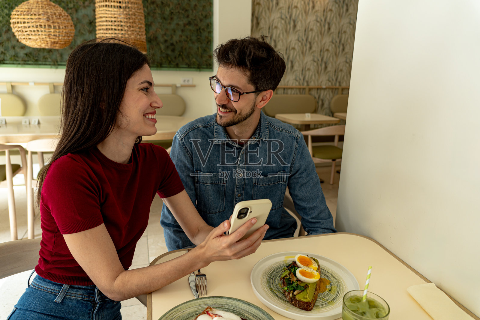 情侣在现代餐厅享用早餐并在手机上分享有趣的内容照片摄影图片