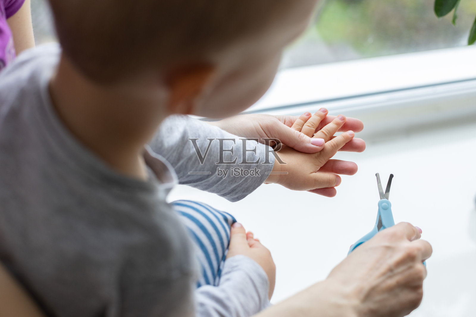 母亲为孩子剪指甲。照片摄影图片