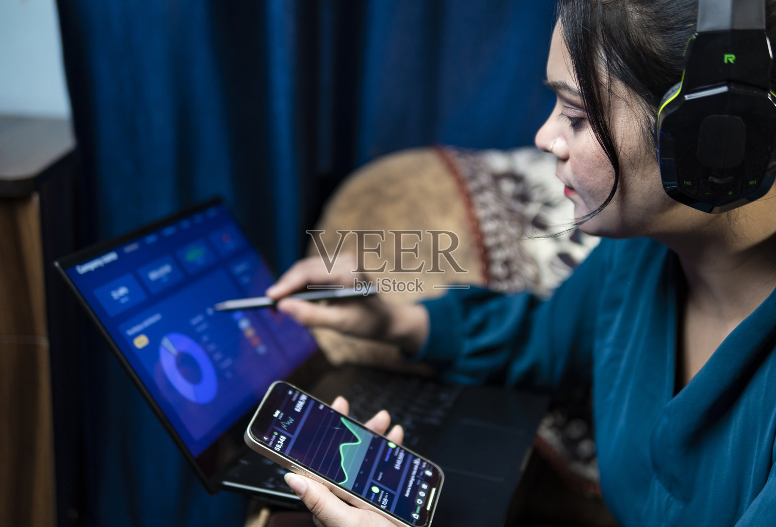 年轻女性在笔记本电脑和智能手机上分析金融交易图表。投资股市。照片摄影图片