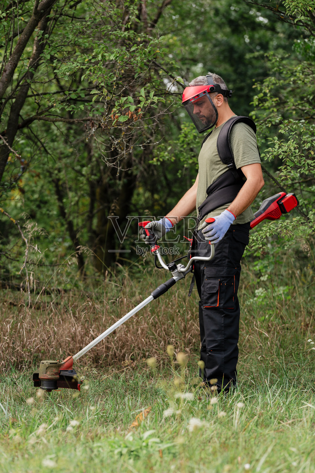 男子在草地上使用割草机维护景观照片摄影图片