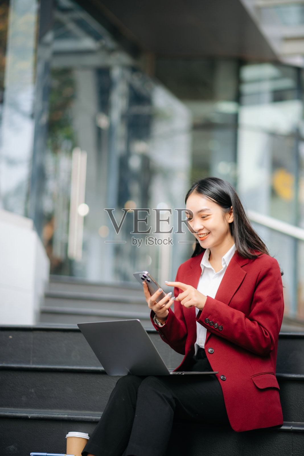 职场女性概念，一位女经理正在参加视频会议，同时手持平板电脑和智能手机。照片摄影图片