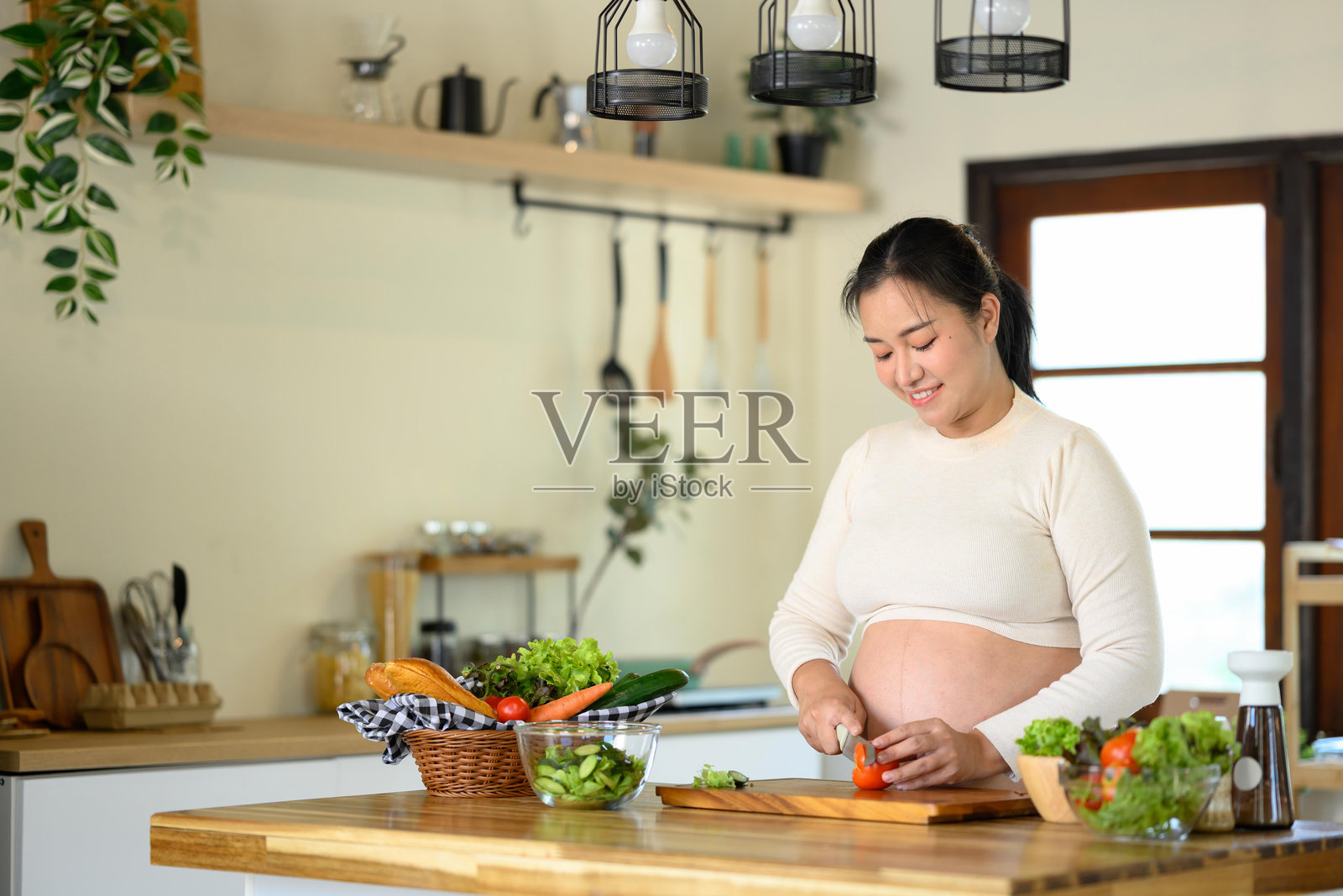 快乐的孕妇在家准备健康沙拉照片摄影图片