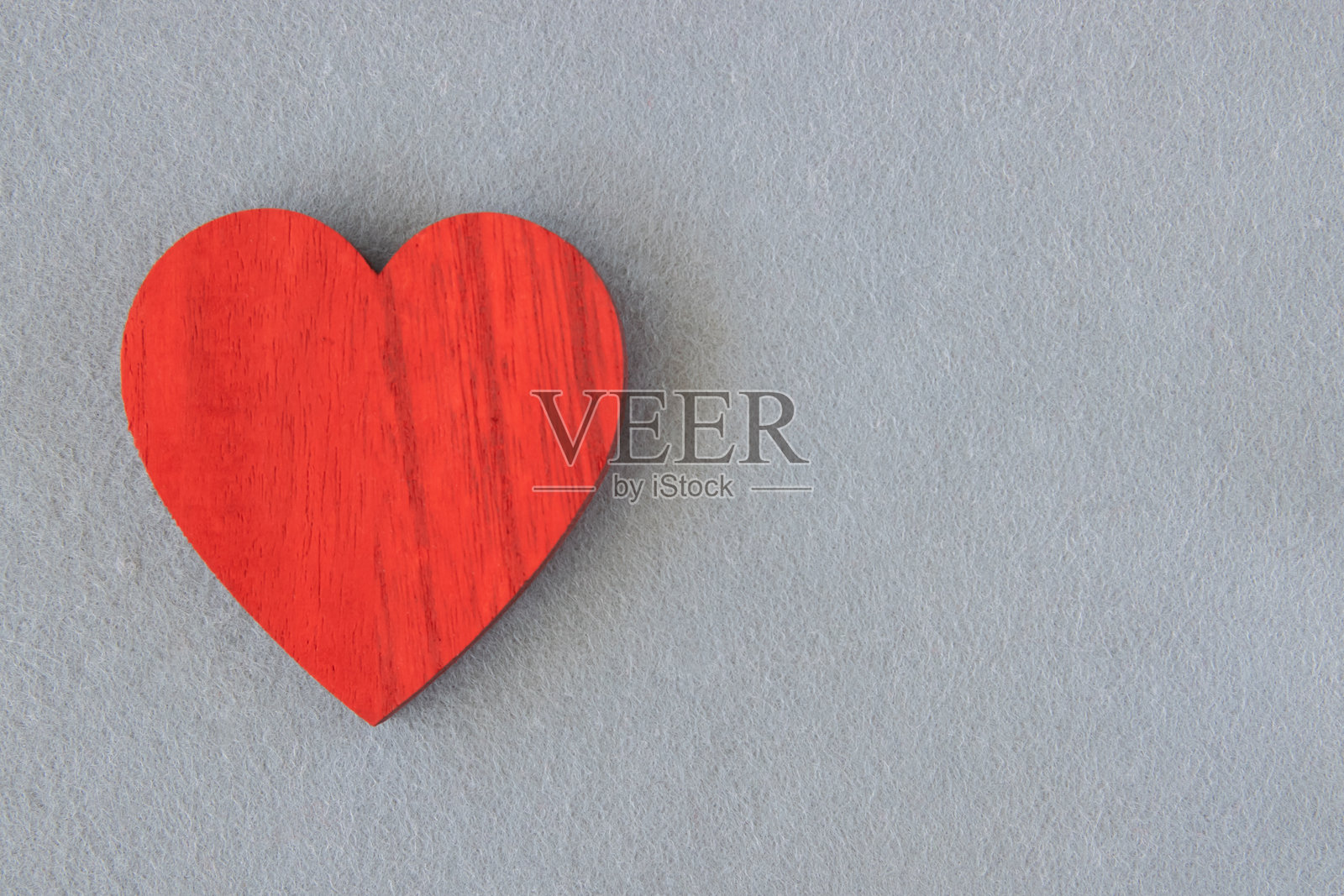 灰色布料背景上的红木心形，留有文字空间。照片摄影图片