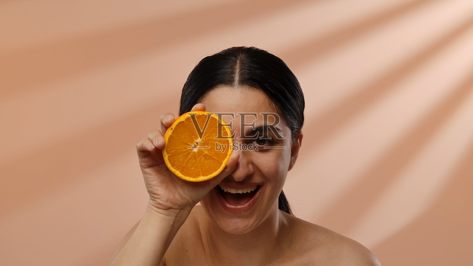 微笑的女人用橙子片挡住眼睛照片摄影图片