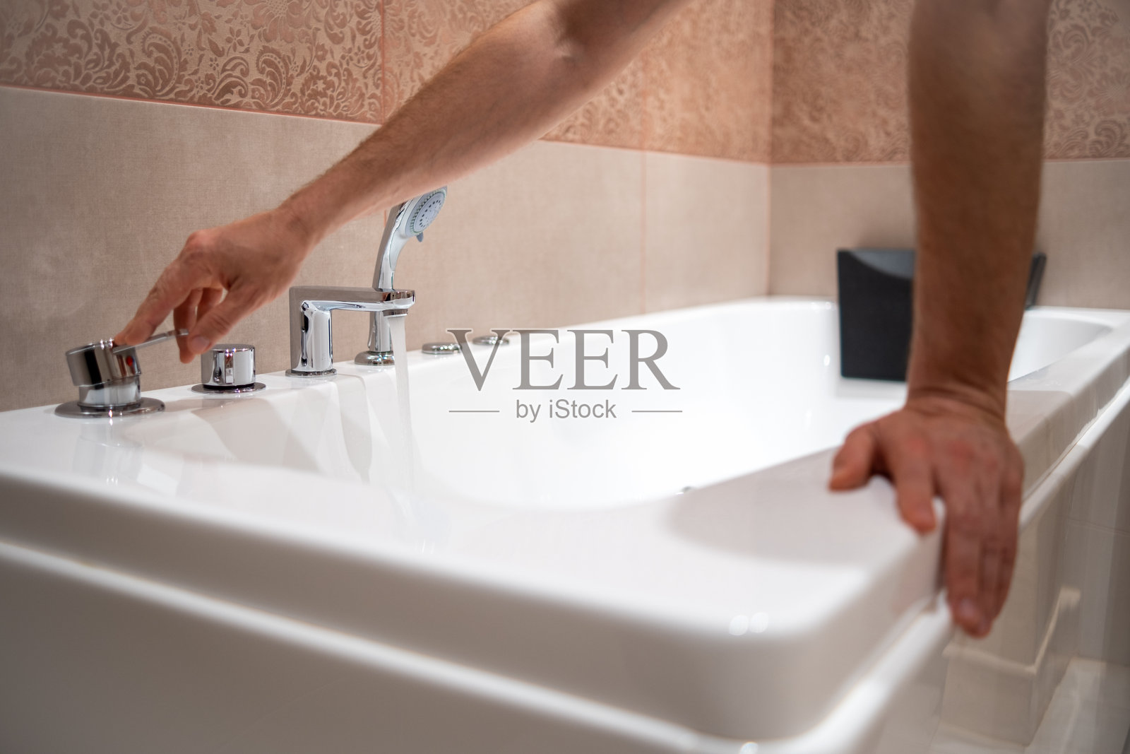 一个男人正在浴室里给浴缸注水。照片摄影图片