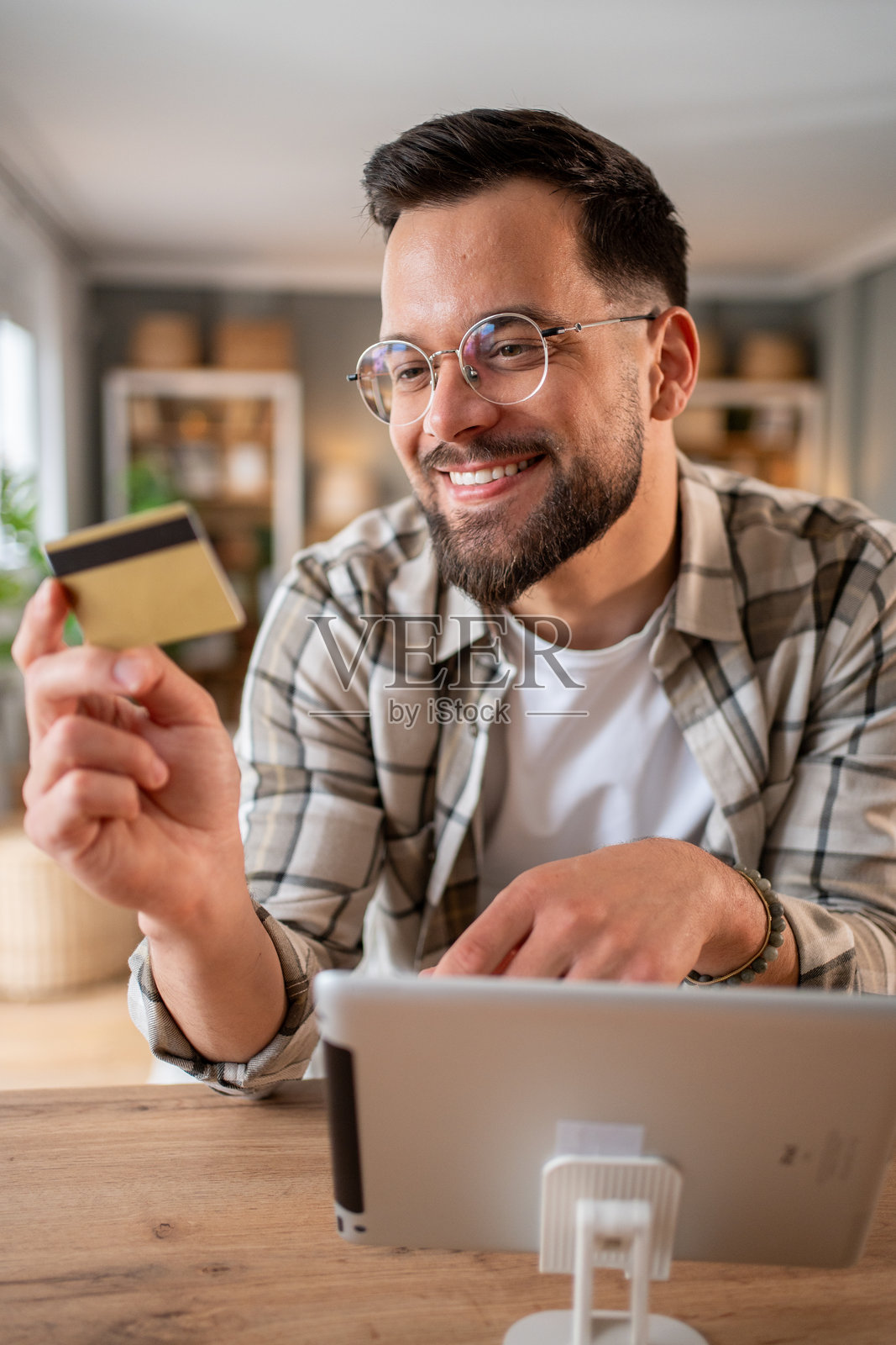 微笑的男子在家中使用平板电脑和信用卡进行在线购物照片摄影图片