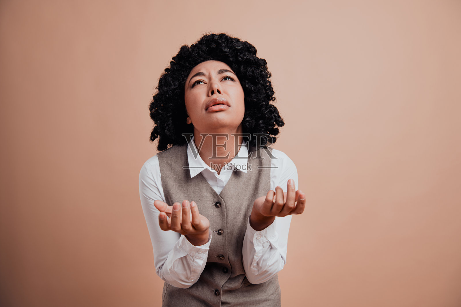 优雅的女商人穿着正式服装，在中性色的米色背景下表现出情感和自信，手势表达丰富。照片摄影图片