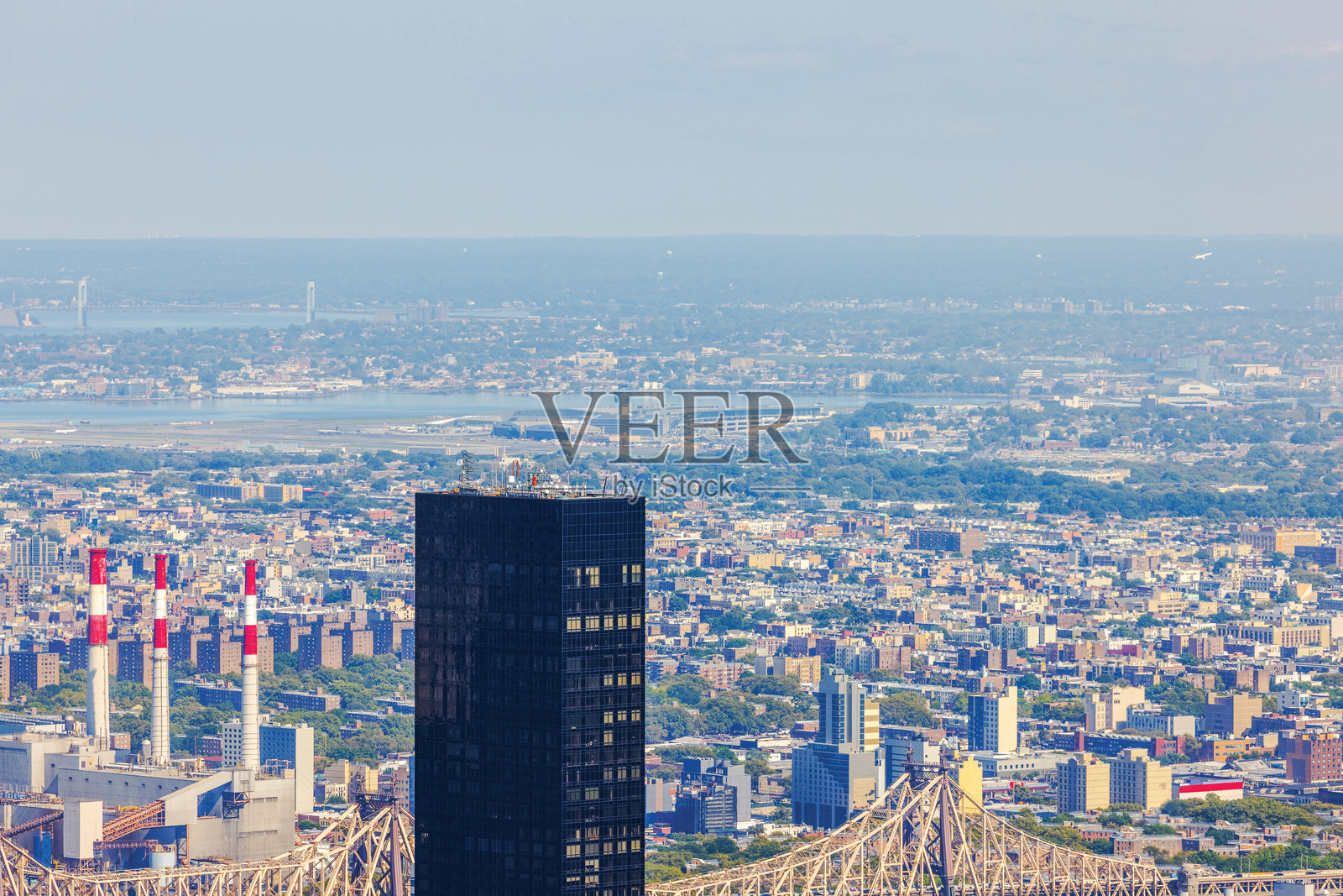 远处的纽约市摩天大楼、发电厂和维拉扎诺大桥在雾霾中。照片摄影图片