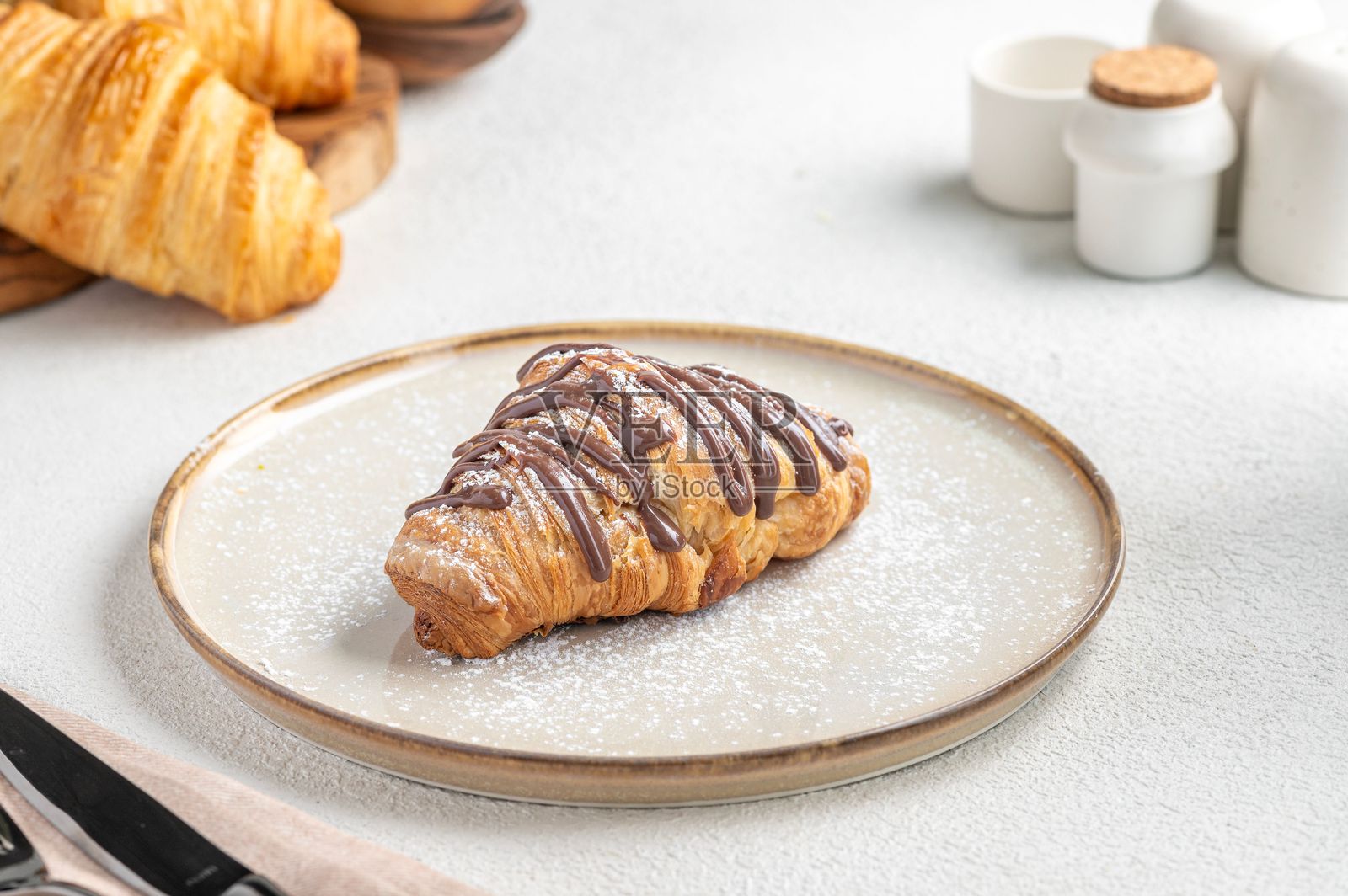 巧克力淋酱的可颂面包放在盘子上。照片摄影图片