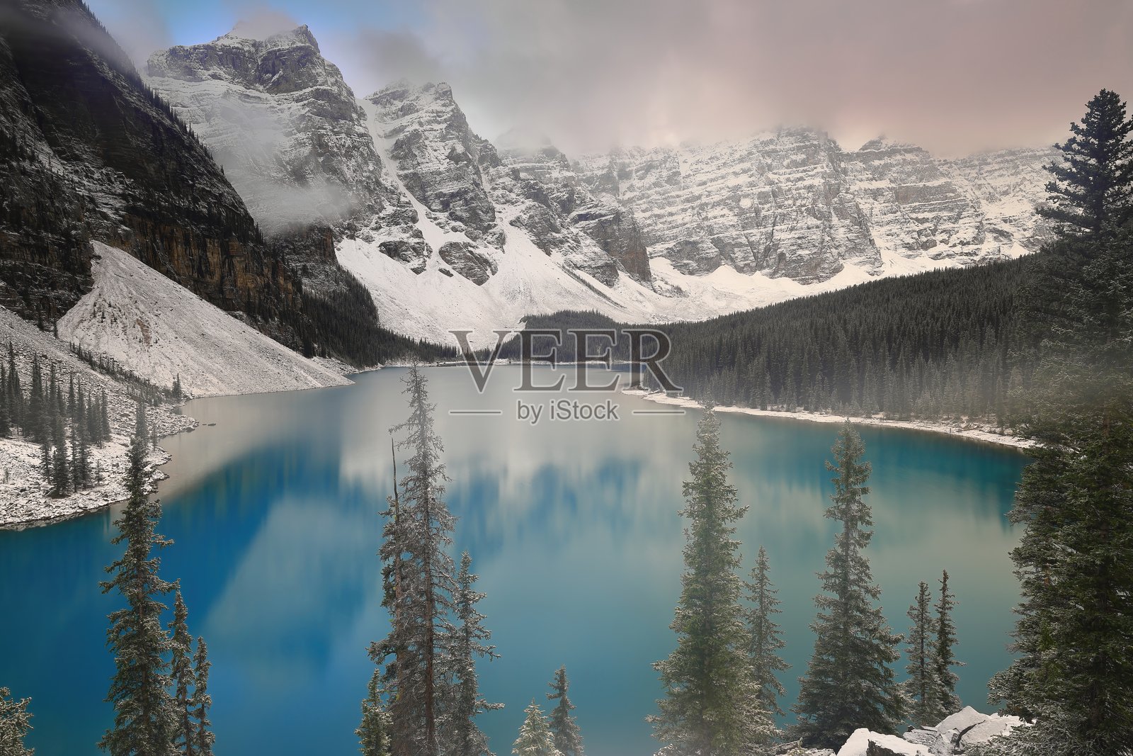 在大雪过后，晨雾笼罩着莫雷恩湖，湖水呈现出碧蓝色，映衬着后方的十峰山脉。班夫国家公园，阿尔伯塔省，加拿大。照片摄影图片