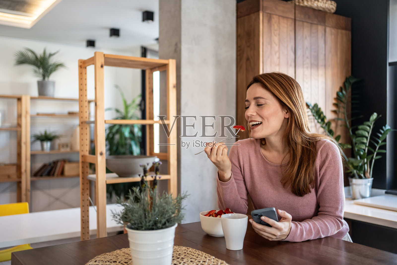 快乐的女人享受早餐并查看手机照片摄影图片