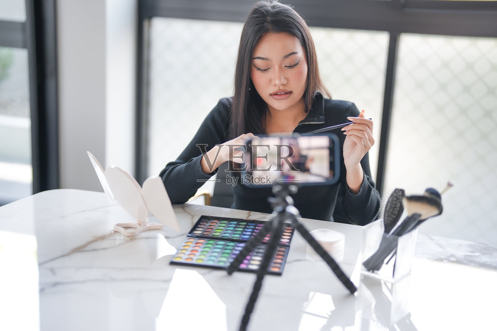 年轻的亚洲女孩化妆师，职业女性博主和视频博主正在展示化妆品产品并录制视频，美容影响者亚洲女孩在线营销视频照片摄影图片