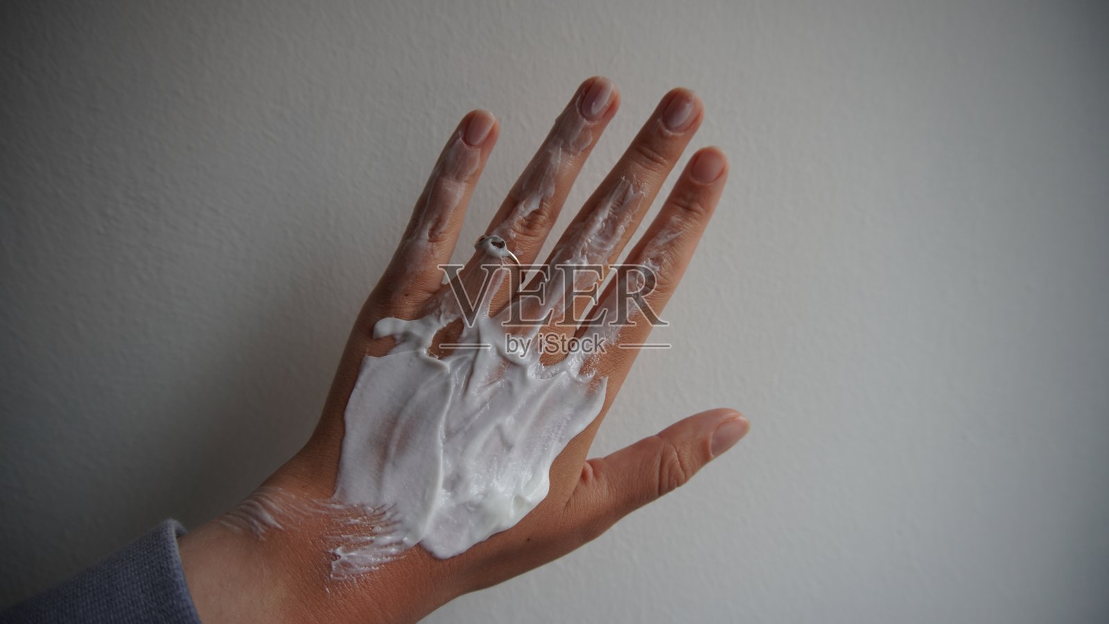 一只女性的手背上涂抹着白色护肤霜的特写，突显护肤、柔软和美容护理仪式。照片摄影图片