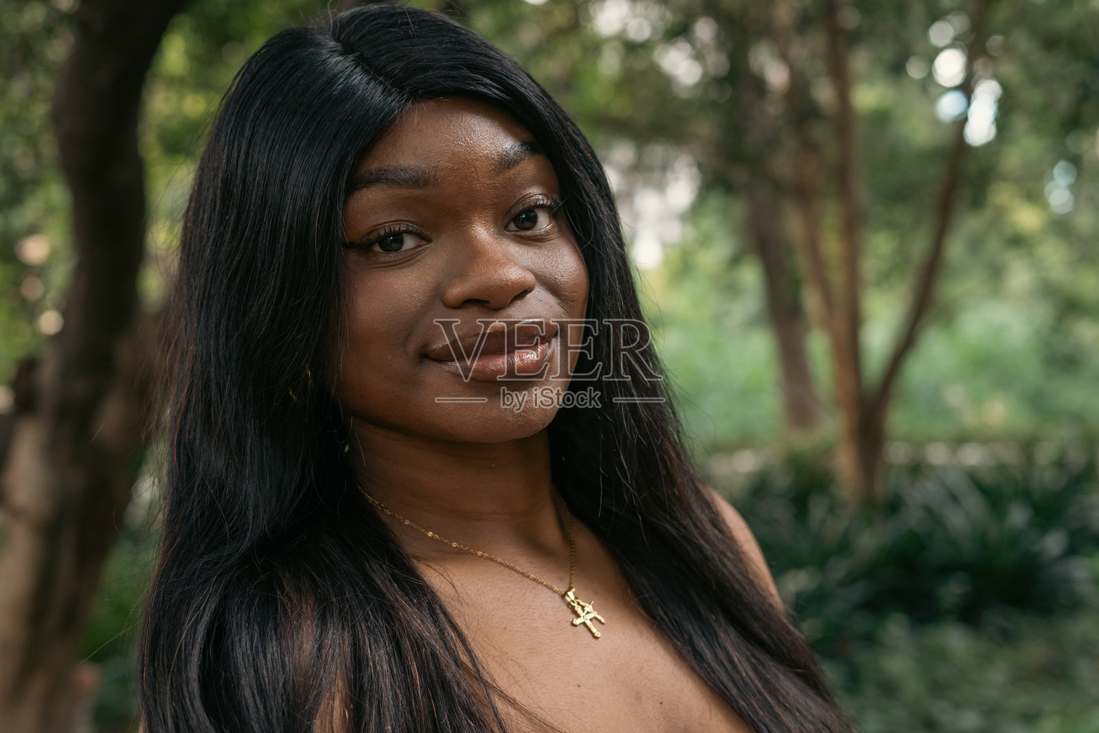 年轻的黑人女性在公园里微笑，佩戴着十字架项链。照片摄影图片