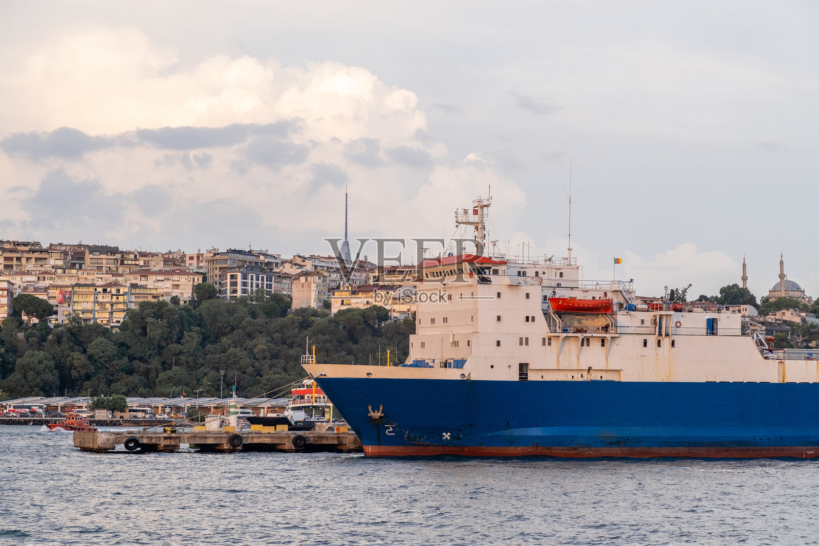 博斯普鲁斯海峡展示了一艘大型货船，背景是生机勃勃的伊斯坦布尔天际线，白天时分。照片摄影图片