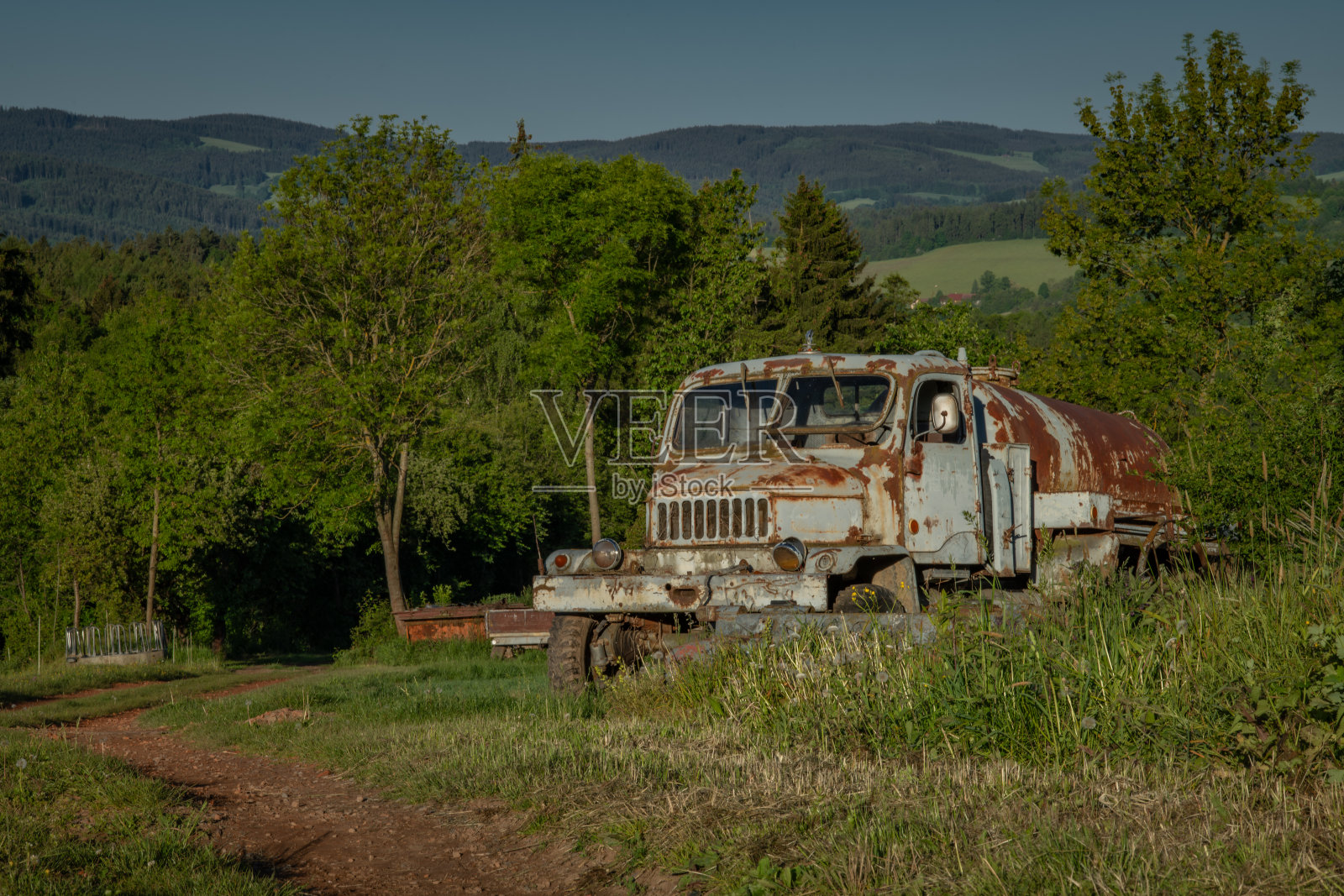 春天清晨，奥多列诺夫的生机盎然的绿草地上停放着旧旧的生锈车辆。照片摄影图片