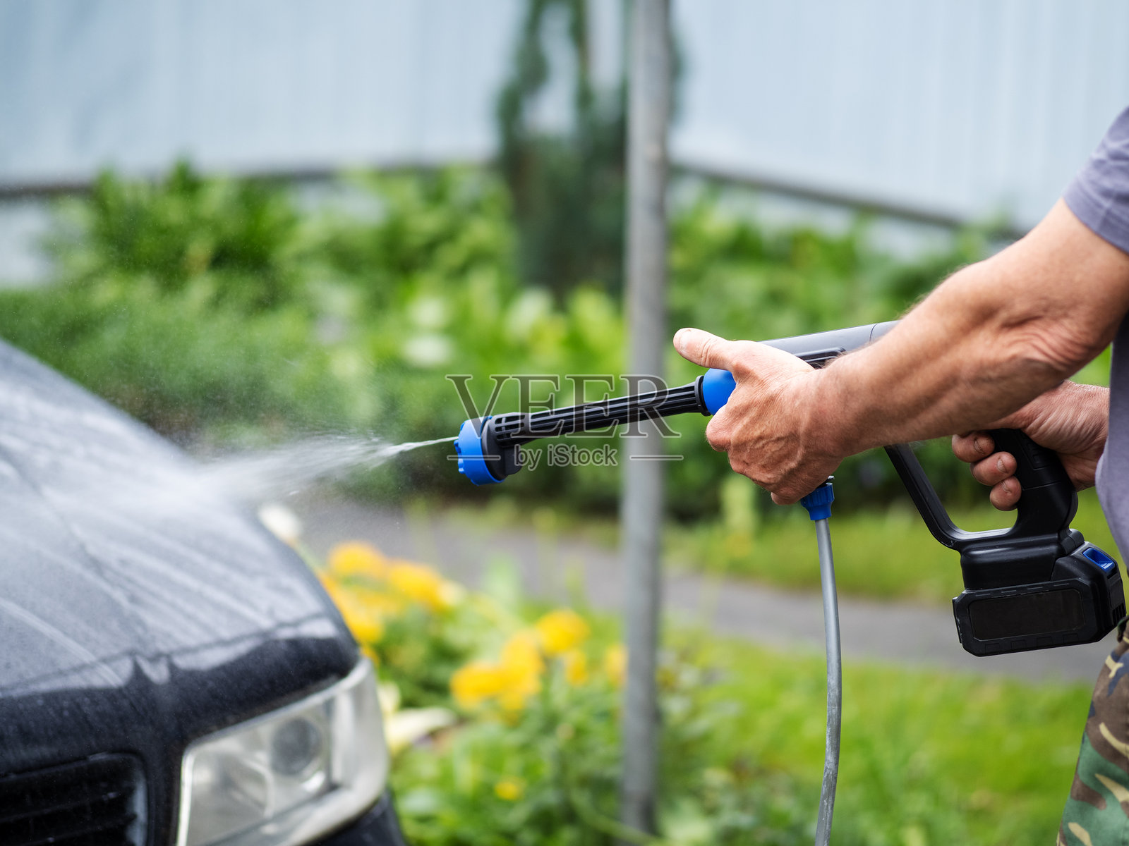 男子使用电池驱动的高压清洗机洗车照片摄影图片