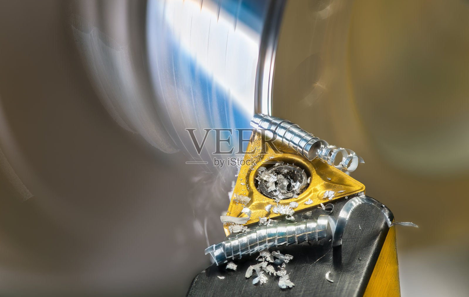 车床刀具特写，金属屑卷曲成螺旋状，正在旋转的工件上。照片摄影图片