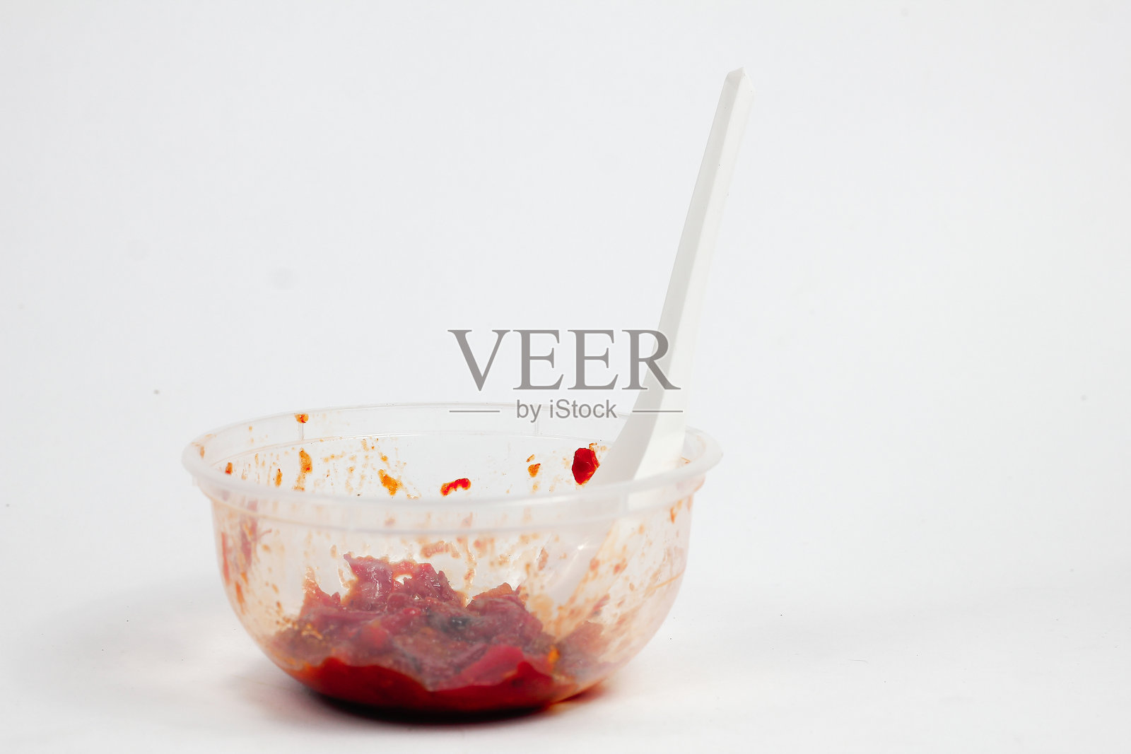 白色背景上孤立的塑料微米容器中的辣味洋葱辣椒酱照片摄影图片