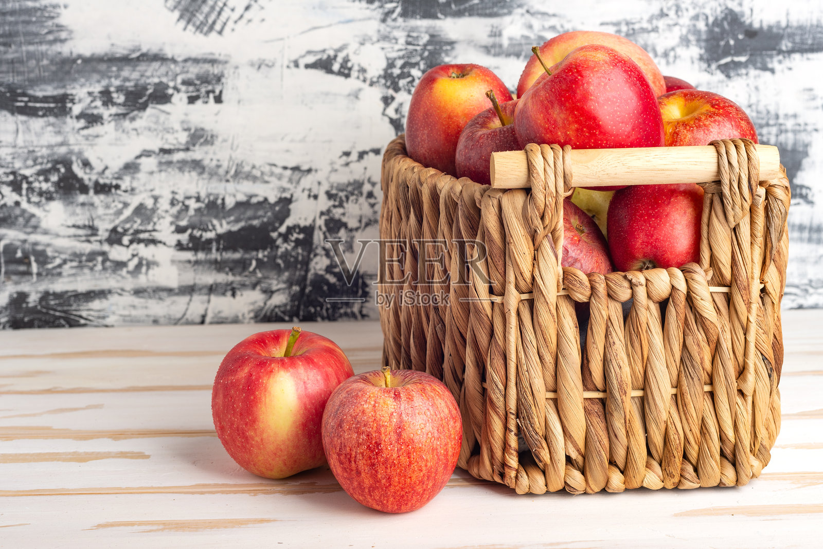 白色桌子上的柳条篮中装满新鲜苹果。留有文字空间。照片摄影图片