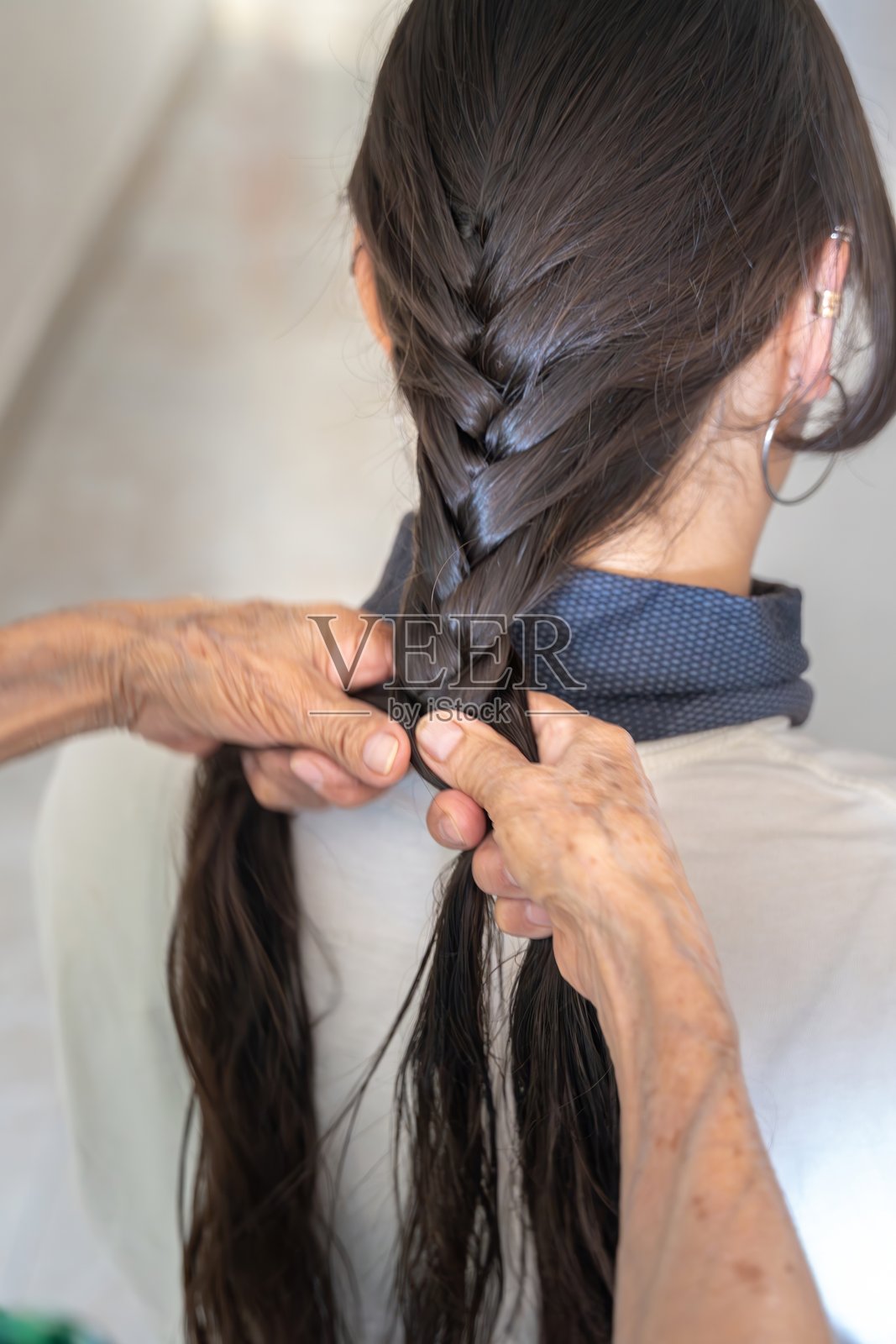 老年人的手在编织长发。发型，造型。手在做发型。照片摄影图片