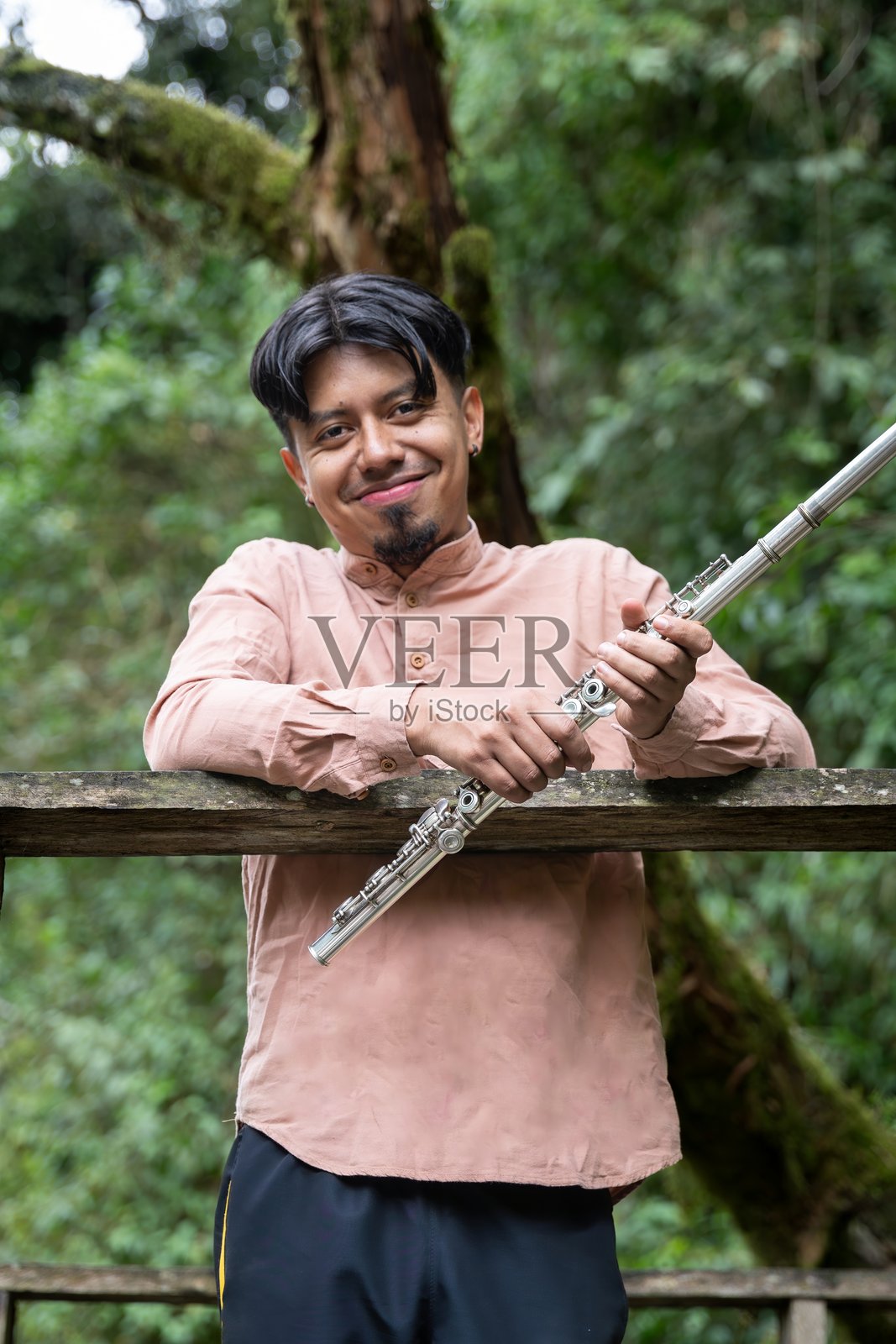 微笑的音乐家在自然中手持长笛照片摄影图片