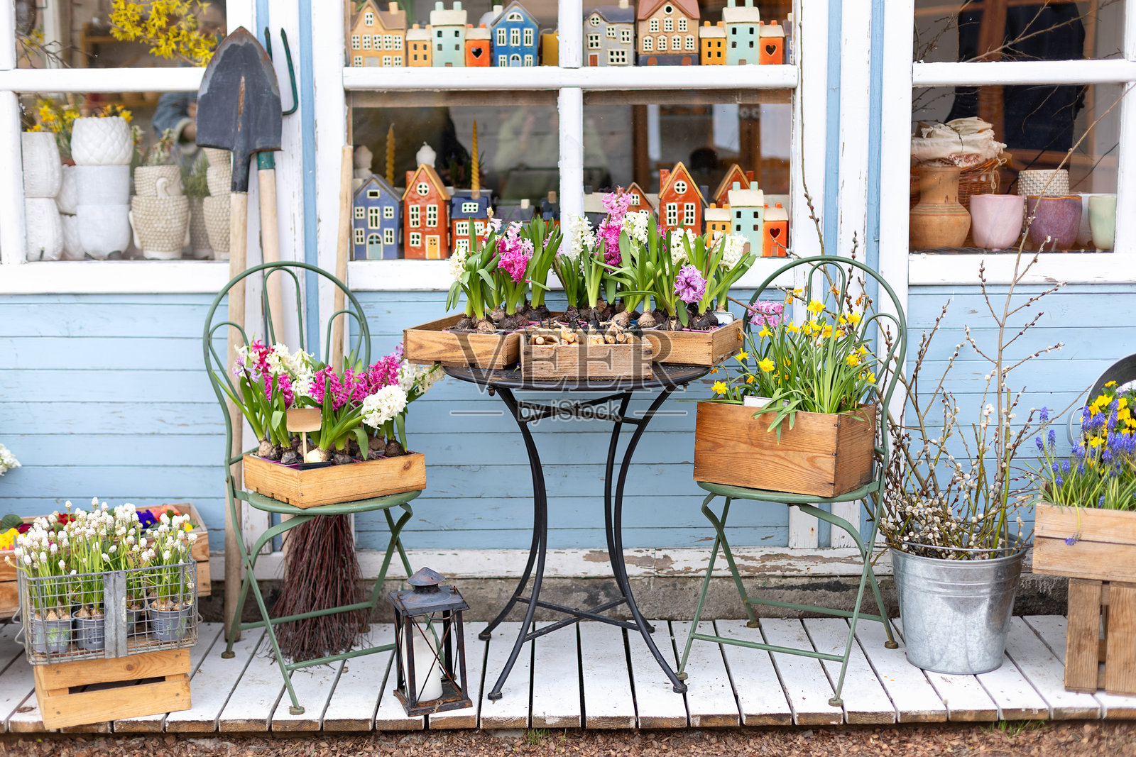 户外市场内有花卉和植物。春季户外家居装饰。阳台上的桌椅供人放松。温馨的家居外观配有花园家具。阳台上有风信子盆栽的农舍。照片摄影图片