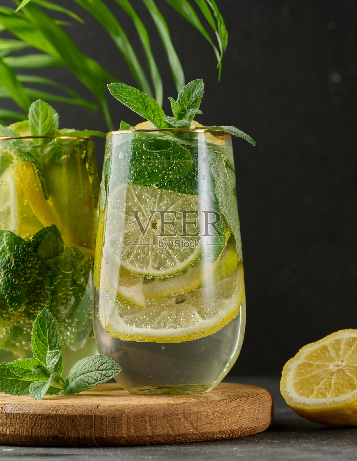 清爽的排毒饮品或夏季饮料，杯中有柠檬、青柠、薄荷、冰块和金属吸管。照片摄影图片