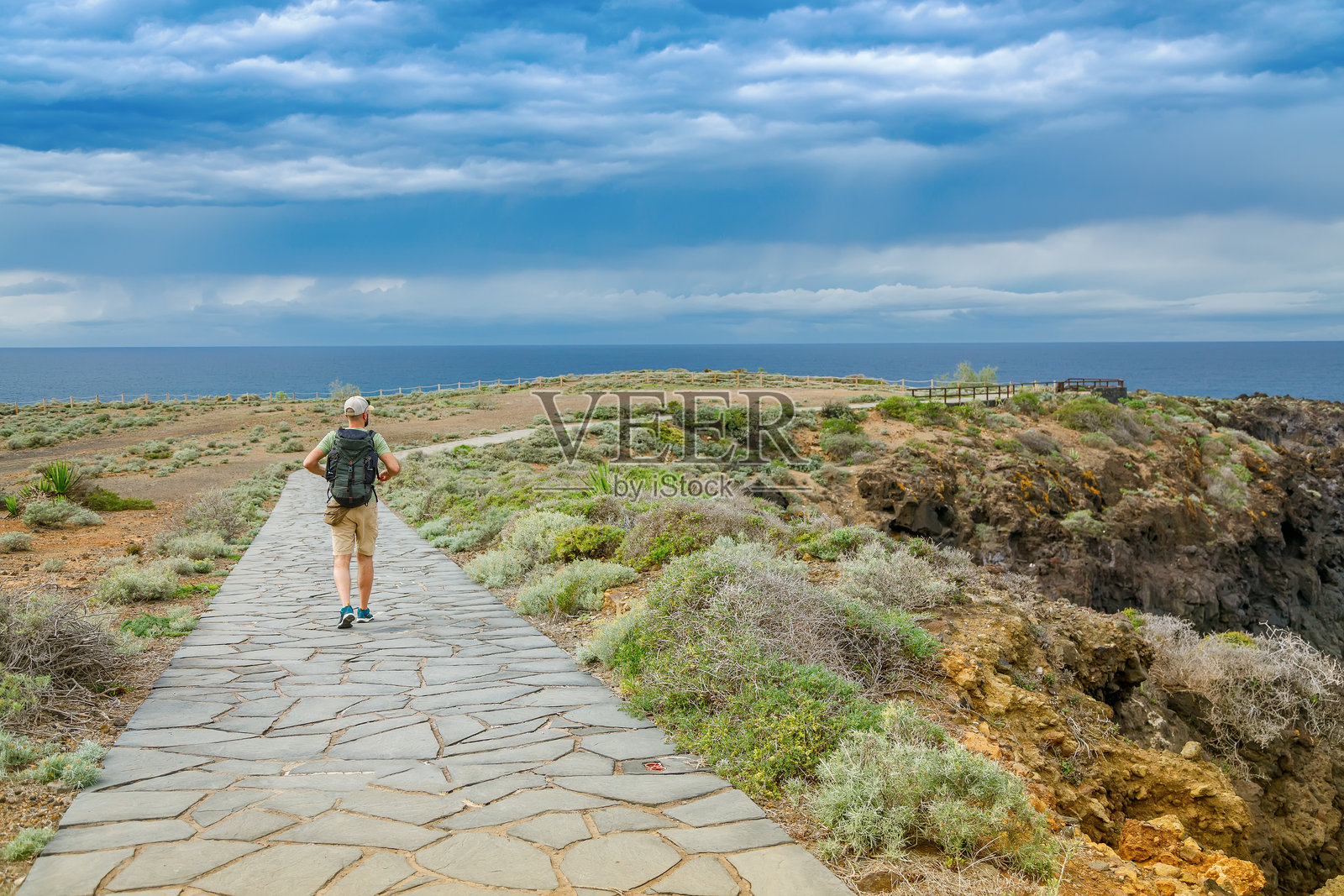 一名独自旅行的男子探索特内里费岛埃尔索萨尔的风景悬崖，石铺小道穿过郁郁葱葱、崎岖的海岸地形。照片摄影图片