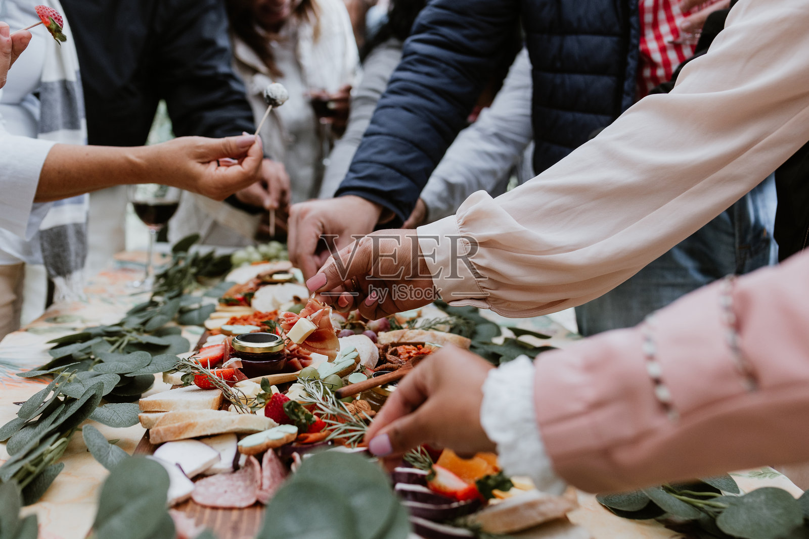 户外木桌上的手和肉类拼盘，搭配葡萄酒和奶酪照片摄影图片