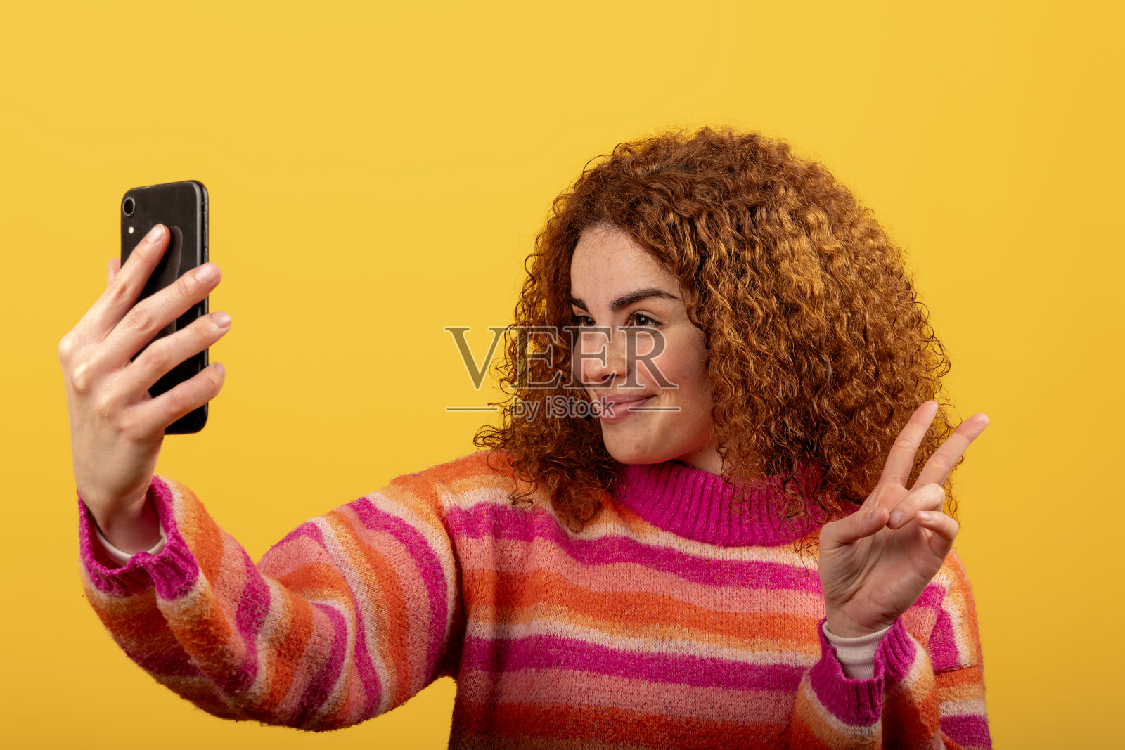 红发女性在黄色背景下做出胜利手势自拍照片摄影图片