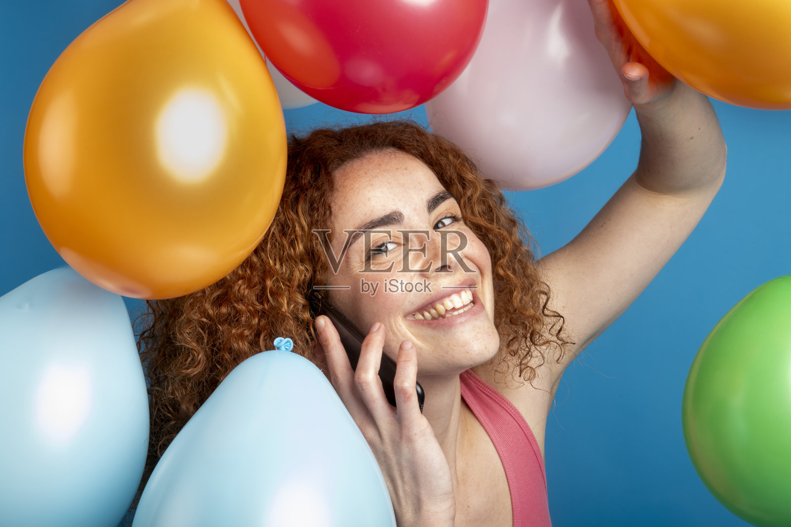 快乐的红发女性在五彩气球中打电话照片摄影图片
