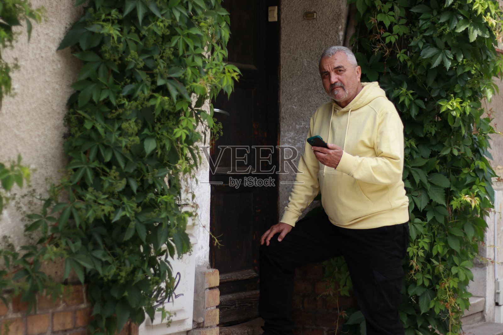 老年男子在街上使用智能手机，面露积极情绪照片摄影图片