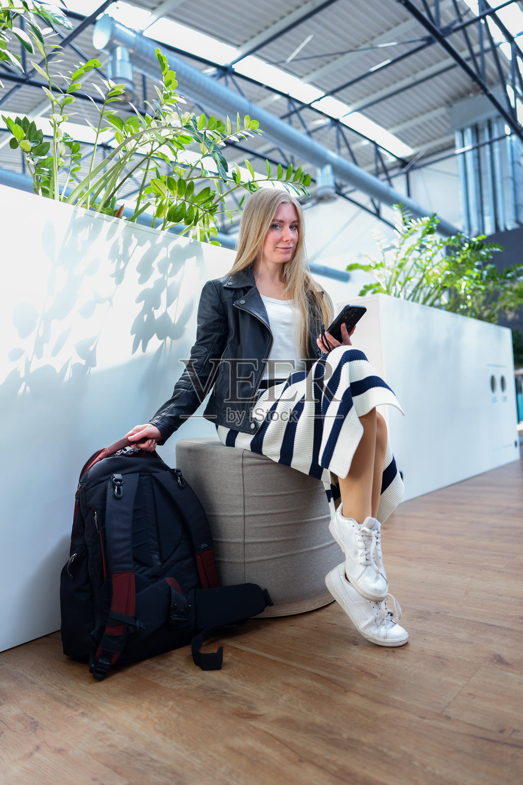 独立女性在明亮的室内空间中，墙上投射着植物的阴影，旅行或共享办公的概念。照片摄影图片