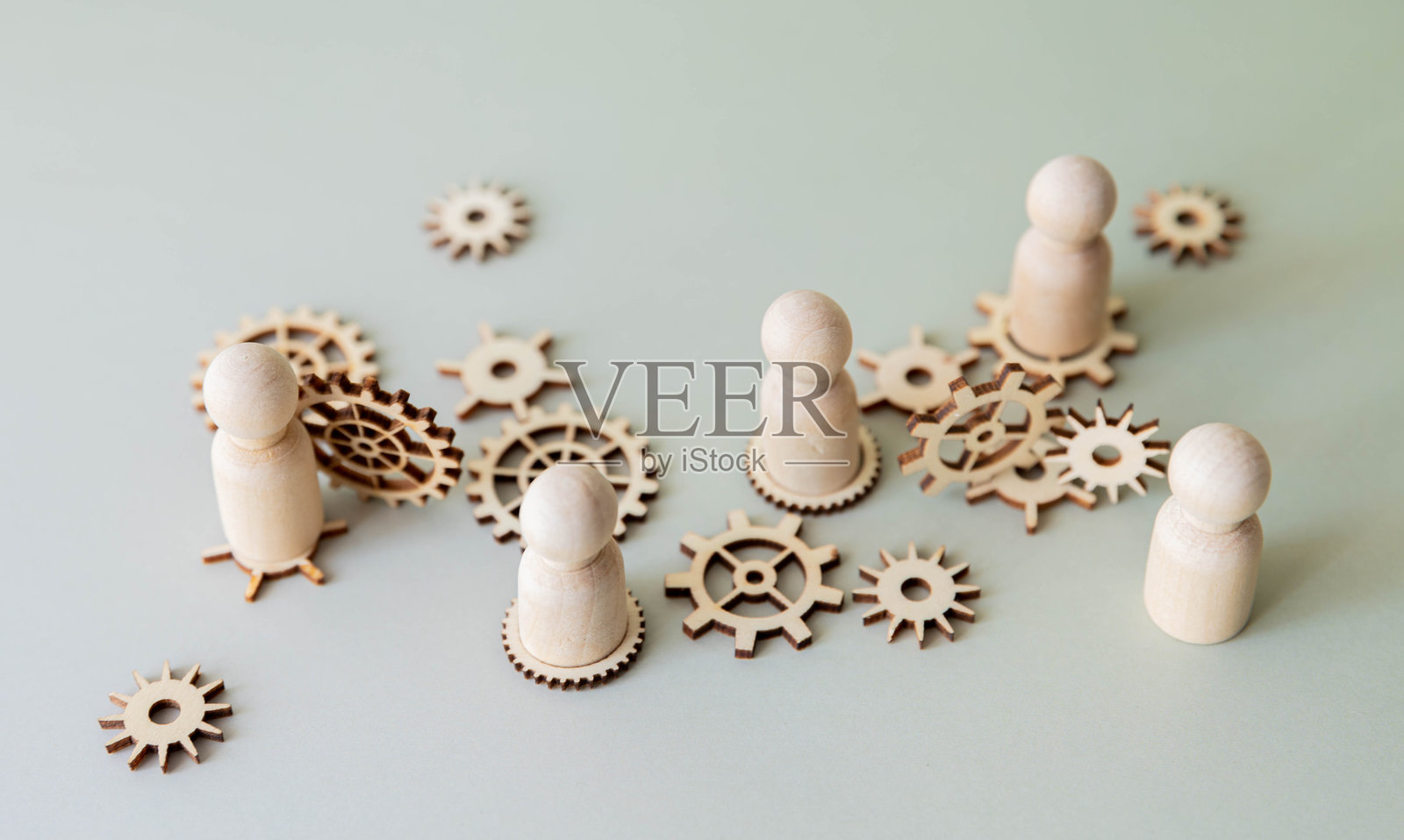 一个概念图，木制人偶站在相互连接的齿轮上。团队合作照片摄影图片