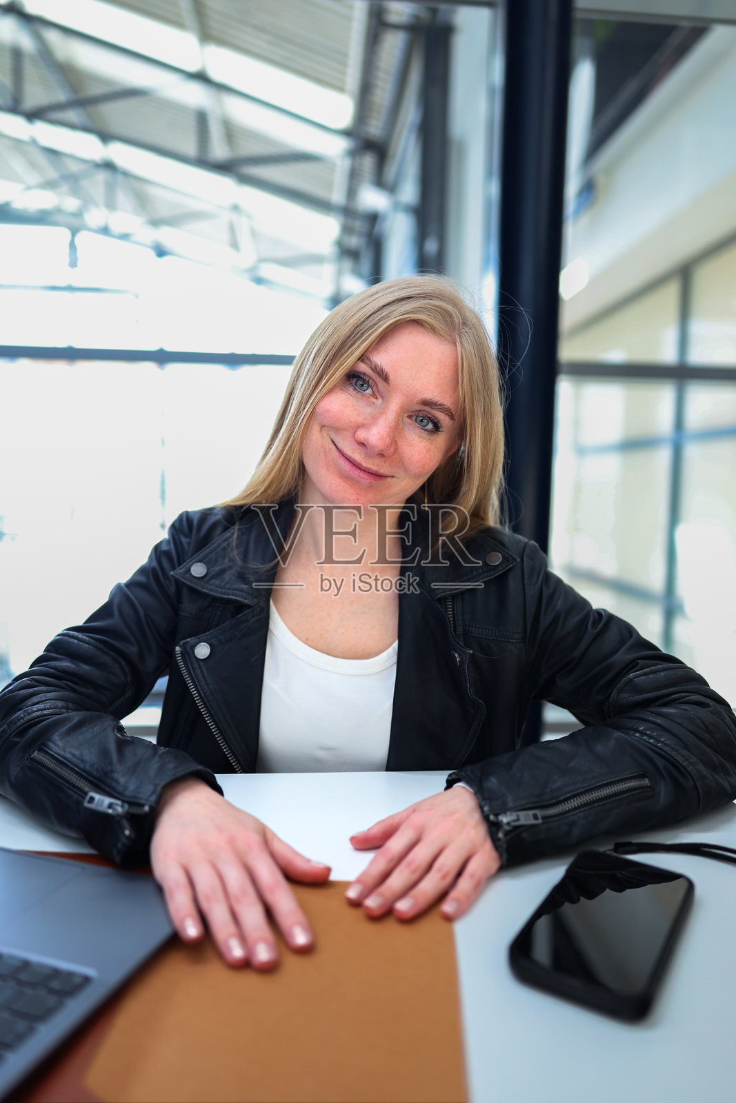 在共享办公空间中，女性微笑着使用笔记本电脑度过轻松的工作日。照片摄影图片