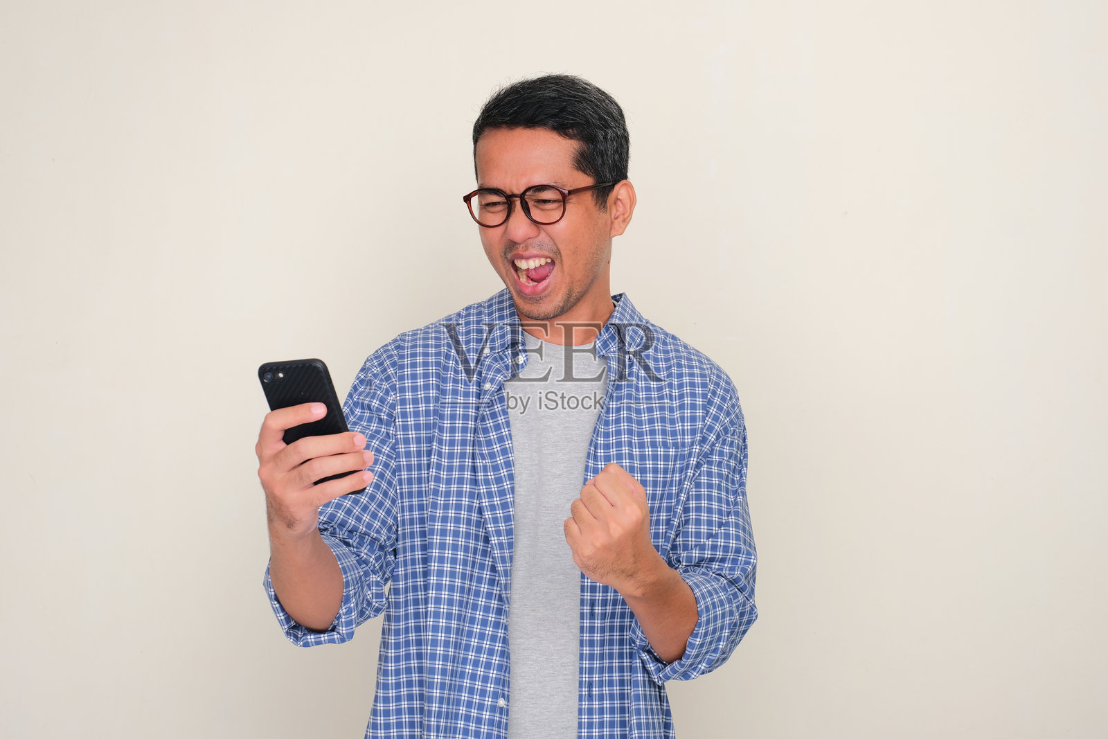 一位亚洲成年男性在看手机时露出兴奋的表情照片摄影图片