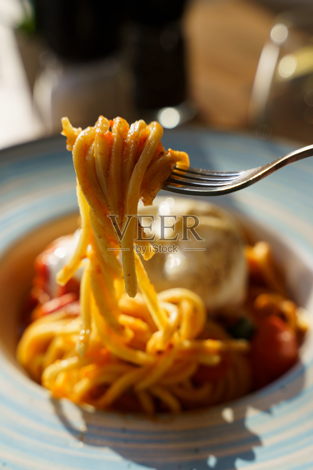 用叉子夹起意大利面，配以布拉塔奶酪和番茄酱照片摄影图片
