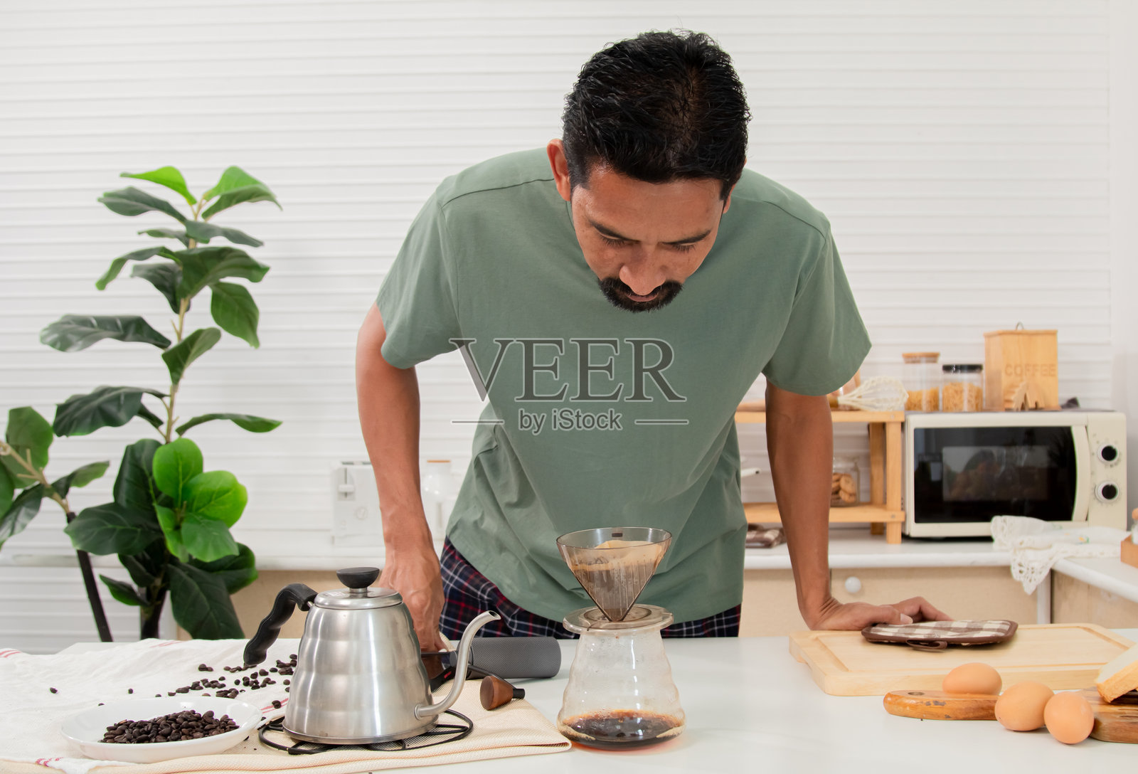 中年有胡子的亚洲男子闻着自己烘焙的咖啡香气。享受早晨的咖啡。早晨的美味与甜蜜。在家度假的生活方式概念。照片摄影图片