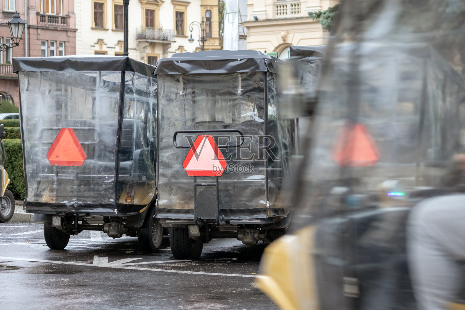 几辆带有橙色三角警告标志的垃圾或货物手推车停放在城市街道上。照片摄影图片