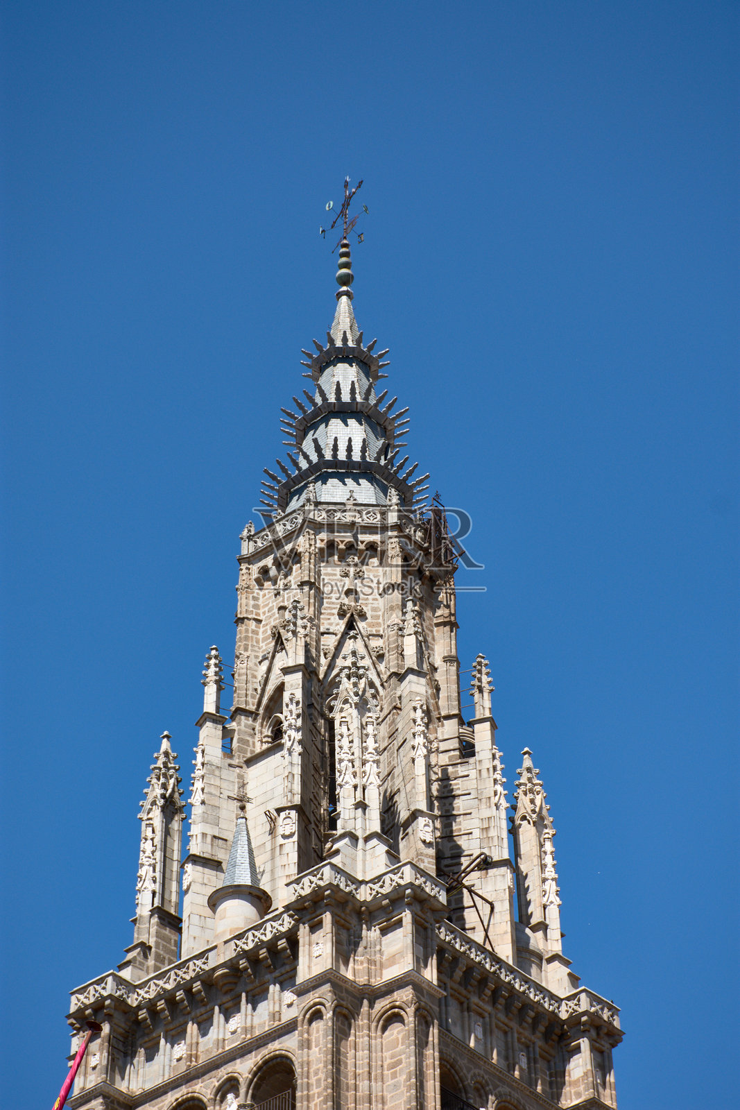 西班牙托莱多大教堂钟楼的复杂哥特式尖塔在晴朗的蓝天中高耸。照片摄影图片