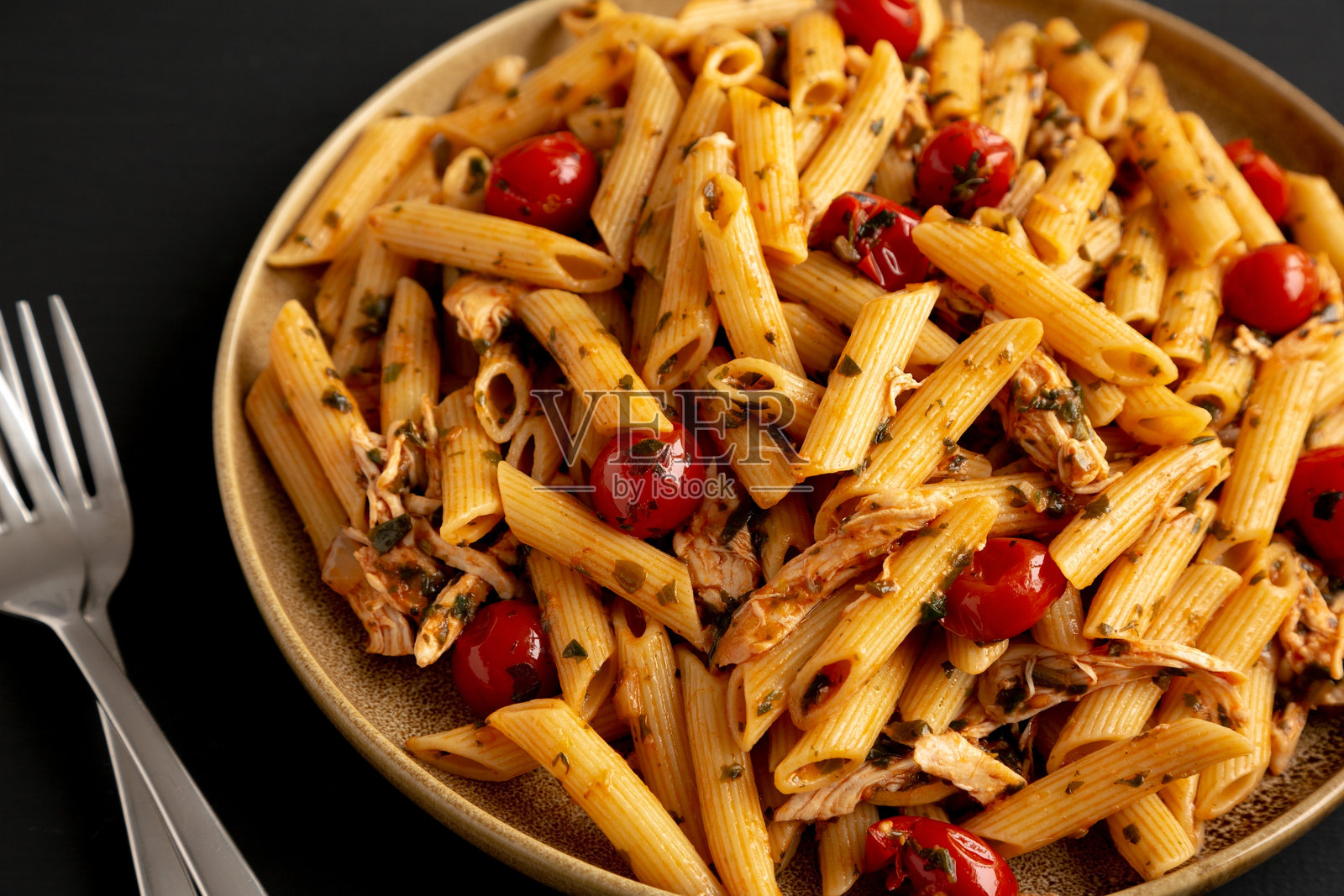 黑色背景下的盘子里盛着自制的一锅菠菜番茄意大利面，侧面视图，特写。照片摄影图片