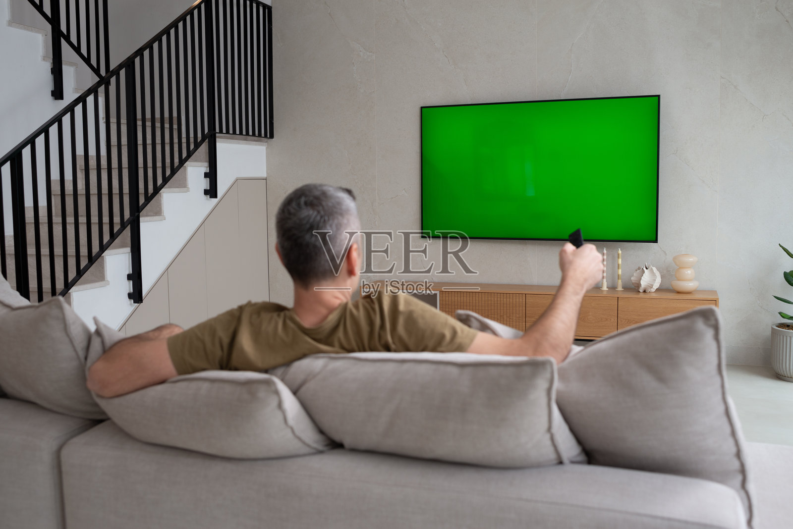 现代客厅中放松的男人与遥控器。照片摄影图片